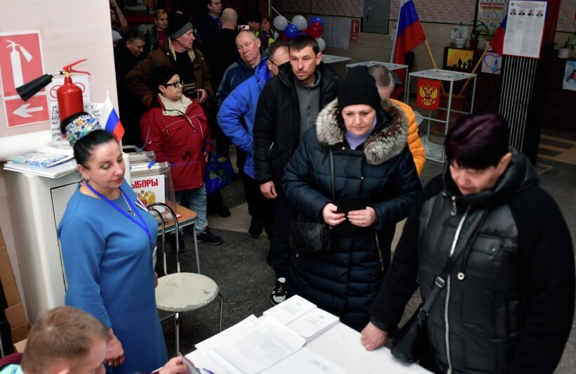 Люди голосуют на выборах президента России на избирательном участке в Херсонской области. Фото